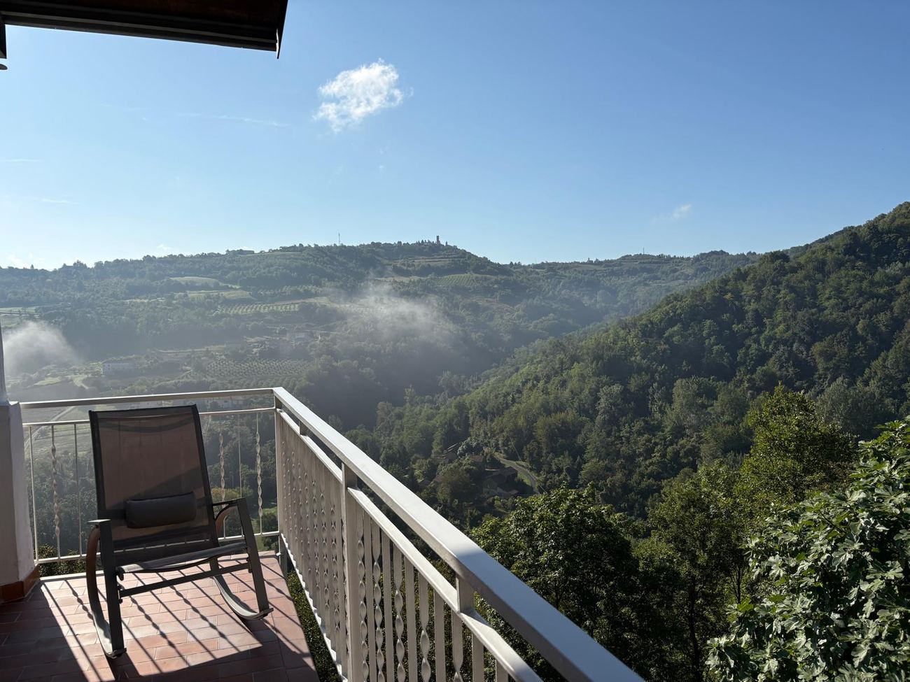 Balkon mit Stuhl und Blick über das neblige Tal bei Casa Mumu